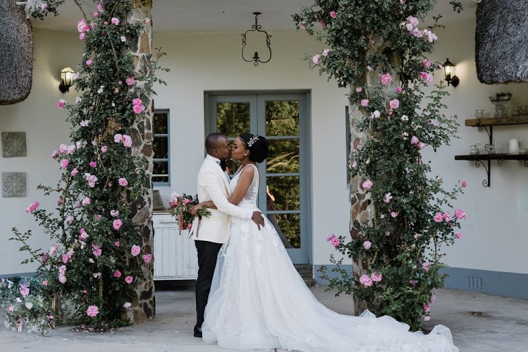 couple kissing under floral arch